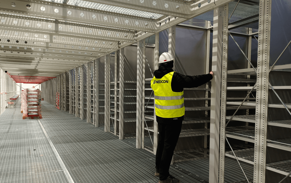 mężczyzna dokonuje pomiarów regałów w magazynie